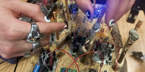 Hands with painted nails manipulating cat's whisker wires on the crystal log synth