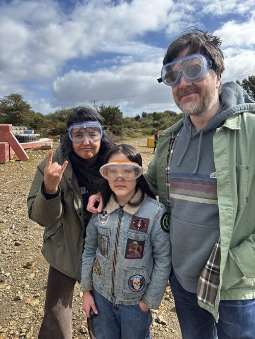 Three people wearing googles surrounded by mine waste